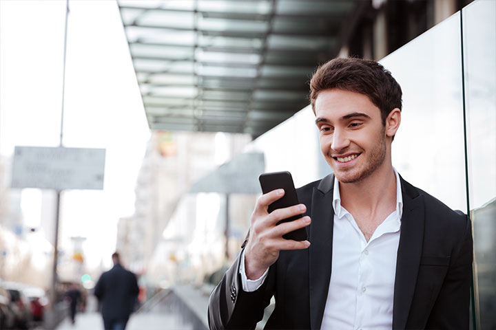 Man looking at his phone while walking in business district.