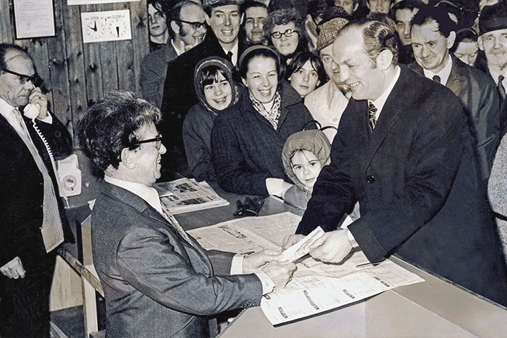 Joe Jennings accepting punter's bet in betting shop.